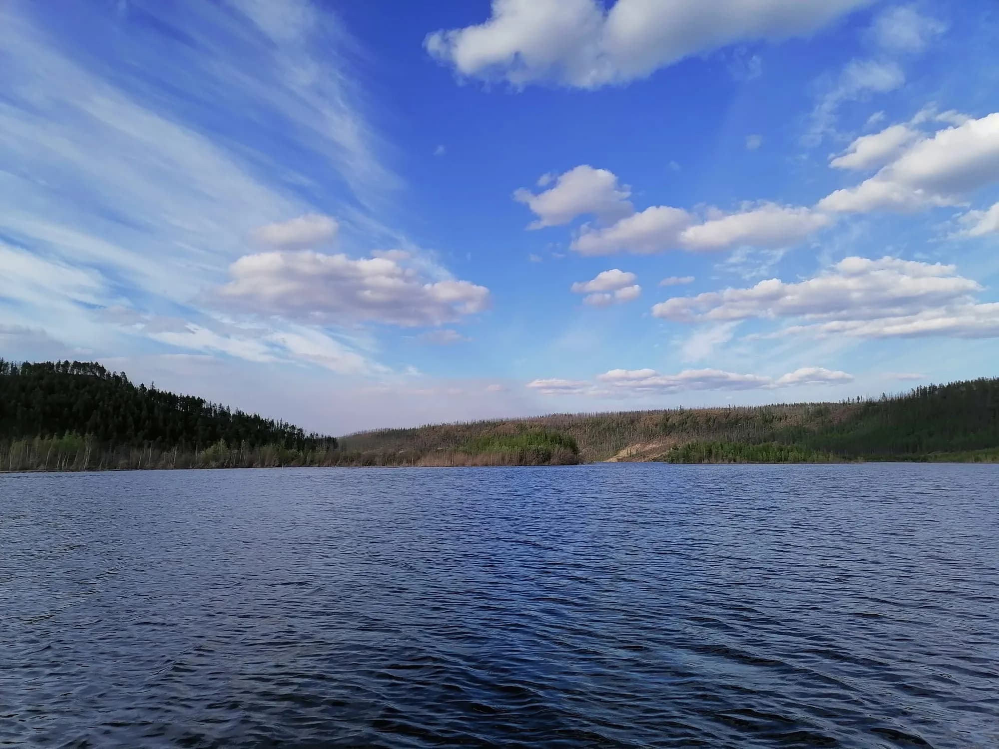Широкая река и лесистый берег под облаками
