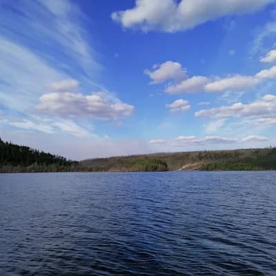 Широкая река и лесистый берег под облаками